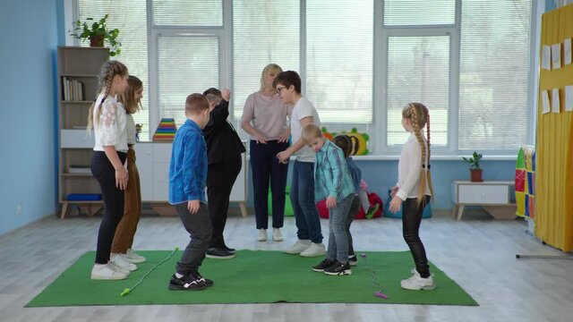 children with down syndrome have fun jumping rope during educational games with teacher in an inclusive school