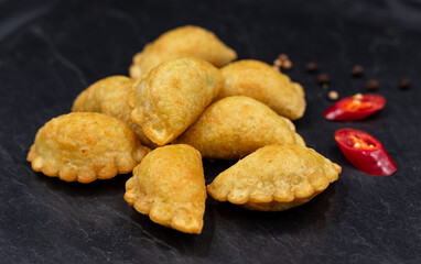 Small chebureks on a black background. Appetizer. Street oriental food.