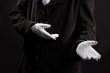 Hand gestures. Showman or magician illusionist in white gloves on a black background.