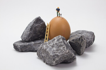 Closeup shot of a small figure of a miner working with rocks on a white background