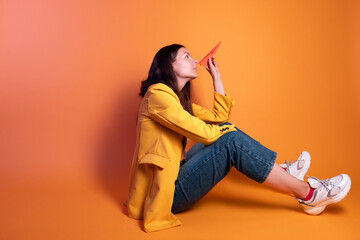 Launch a paper airplane, a dream travel concept. Young brunette woman in yellow