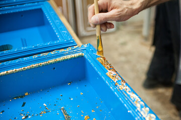 the master uses a brush to cover the wooden billet with gold leaf. Furniture manufacturing