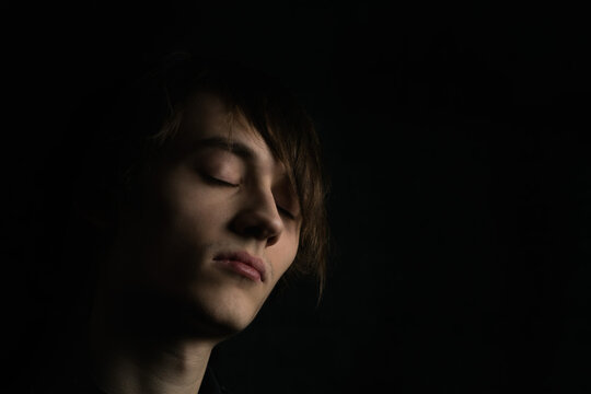 Portrait image of a young guy with long hair on a very dark background