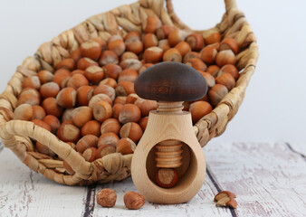 Homemade wooden tool for cracking nuts close-up on a background of hazelnut.