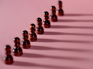 chess pieces in a row, pawns on a pink background,