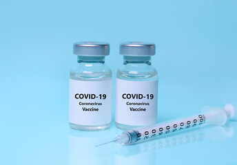 Vaccine in a bottle with a syringe on a blue background. Syringe, two vials (two doses) of coronavirus vaccine.The concept of medicine, healthcare and science.Coronavirus vaccine.