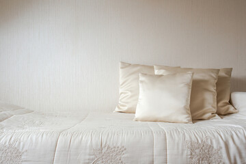 silk pillow and blanket against cream colored wall in bedroom modern and luxurious style, modern...