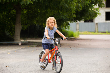 The little girl rides a bike in the city