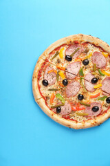 Italian Pizza with homemade sausage, Mozzarella, Bulgarian pepper, Olives, Small cucumbers, Champignons, Oregano. Blue background. Copy Space