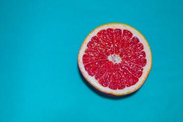 Fototapeta na wymiar Piece of red grapefruit on isolated blue background.