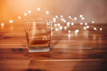 Glass voll whisky auf einem Holztisch mit Lichtern im Hintergrund. Bokeh