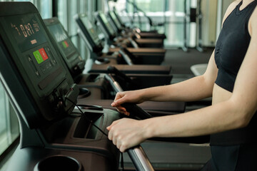 Plakat Happy athletic woman jogging on treadmills in a gym.