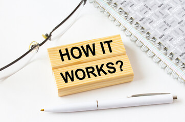 Text How It Works on a wooden blocks lying near notepad with eyeglasses and pen