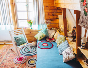 Maximalist maximalist home concept. Holiday home cabin bedroom with natural wooden board walls and ceiling and lot of different color details.
