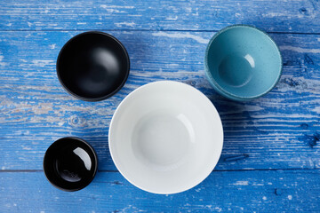 four empty bowls on a blue wooden table - 422639312