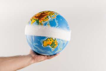 partial view of man holding bandaged globe isolated on grey, ecology concept