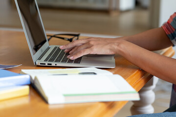 Caucasian woman sitting by desk working from home using laptop