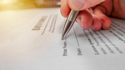 Conceptual image for divorce with a hand signing the contract. Shallow depth of field with...