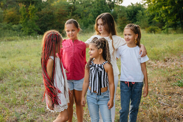 Fototapeta premium A group of cheerful girls are smiling and playing in the Park during sunset. Children's summer camp