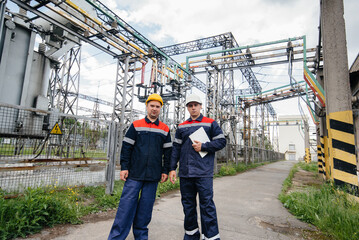 Two specialist electrical substation engineers inspect modern high-voltage equipment. Energy. Industry