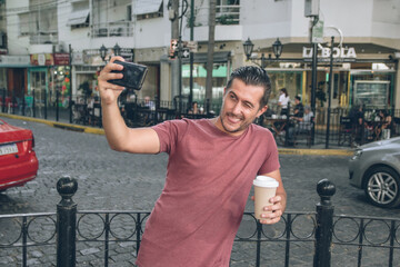 Young hispanic man taking a selfie winking