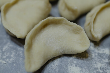 Dumplings with meat on a wooden board with flour.