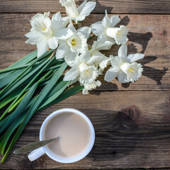 A bouquet of white daffodils and a cup of coffee with milk