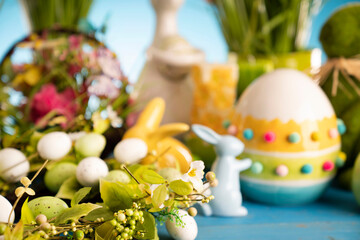 Easter theme. Easter decorations. Easter eggs in basket and cabbage leaf. Bouquet of spring flowers. Blue background.