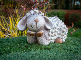 Caen, France, March 2021. Figurine Easter lamb on green grass in the garden, symbol of Easter.