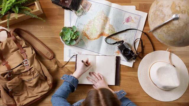 Top view of young woman with maps planning vacation trip holiday, desktop travel concept.