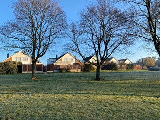 Sunrise with houses and trees in a frosty winter day, sunny morning with trees in English town, long shadowns, suburbia.