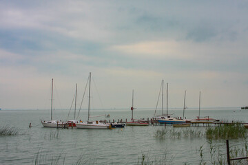 Fototapeta na wymiar Small sailboats moored on the lake of balaton in hungary on a cloudy summer day.