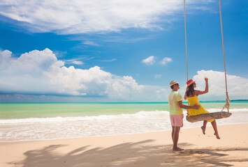 Couple in love on a swing by the sea. Couple in love on an island off the coast. Honeymoon.