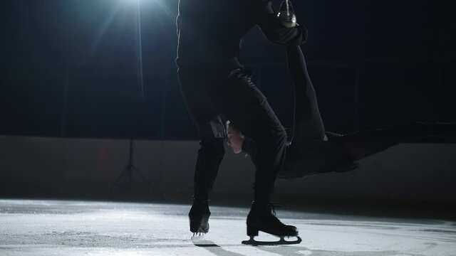 Man And Woman Are Performing Figure Skating Lift And Spin, Professional Pair Skaters Are Training On Ice Rink, Man Is Holding Woman And Rotating