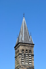 Fototapeta na wymiar Church Steeple with Slate Tiles & Louvred Belfry against Clear Blue Sky