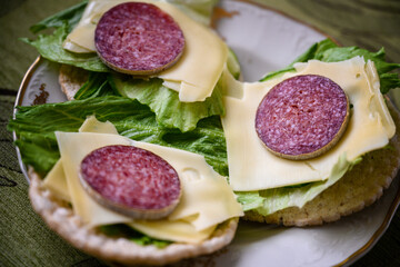 Garnished spelled pancakes with salad, slice of cheese and salami.