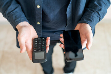person hands holding two cell phones, vintage old and modern new, era difference