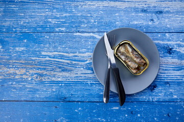 cutlery with canned sardines on a plate - 422648395