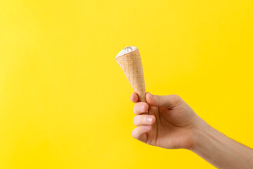 human hand holding ice cream cone isolated on color pastel background, abstract creative idea