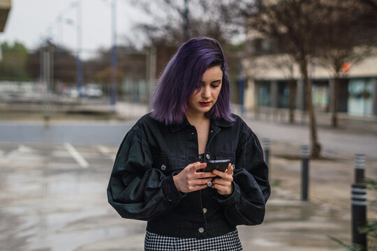 Closeup shot of a Caucasian sexy woman with purple hairs chatting on the phone