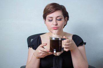 Woman smelling fresh hot coffee in French press with a satisfied face