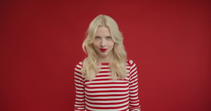 Villain idea. Sly blonde woman conspiring scheming, thinking over tricky plan with cunning expression, pondering revenge or evil prank. Indoor studio shot isolated on red background