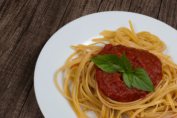 Pasta with sugo sauce with basil leaves. Italian gastronomy. Photograph with space for text on the left.Gourmet Photo. Bavette noodles.