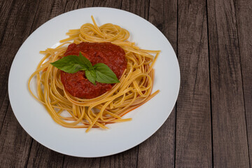 Pasta with sugo sauce with basil leaves. High angle photography in the view of who is eating. Space for text on the right. Fast food.