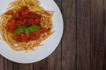 Pasta with rustic tomato sauce and basil leaves. Photograph with elements on the left. Space for text. Italian Pasta. Top view photography for restaurants and cafeterias.