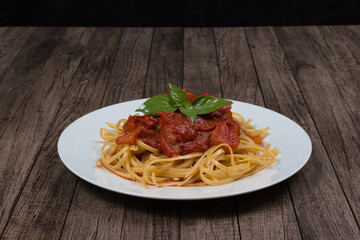 Pasta with rustic tomato sauce and basil leaves. Bavette pasta in red sauce with pieces of...