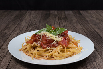 Pasta with rustic tomato sauce, basil leaves and grated cheese. Bavette pasta in red sauce with cheese. Photograph with centralized elements and upper space for text