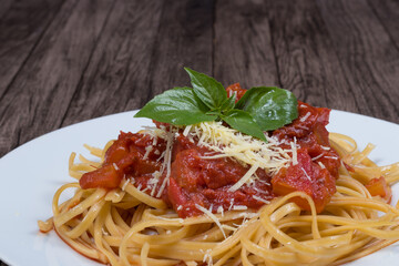 Pasta with rustic tomato sauce, basil leaves and grated cheese. Bavette pasta in red sauce with cheese. Close-up gastronomic photo for restaurants.