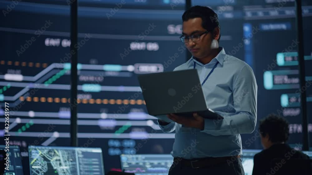 Aufkleber young multiethnic male government employee uses laptop computer in system control monitoring center.
