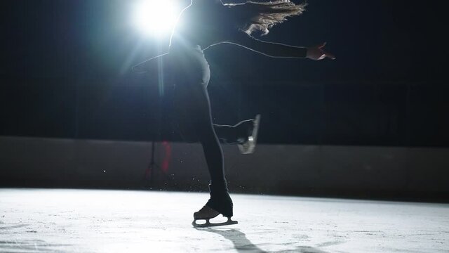 amazing slow motion shot of spinning female figure skater on ice rink, ladies figure skating competition, moving figure against bright soffit